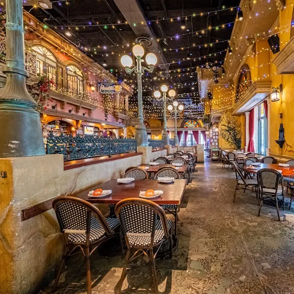 Outdoor restaurant patio at night with string lights and empty tables, warm glow