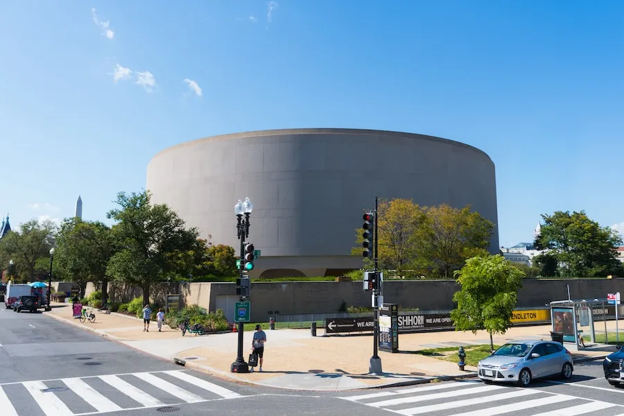 Photo of the Smithsonian Hirshhorn Museum, Washington, DC, with street traffic and crosswalk
