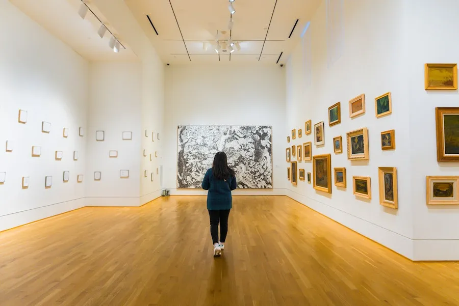 Person walking through bright art gallery in The Phillips Collection with framed works on white walls
