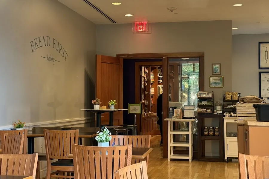Quiet dining area in Bread Furst Cafe with wooden tables and a counter in back.
