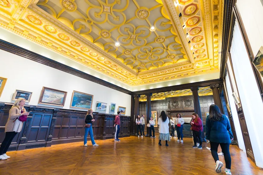 Visitors in The Phillips Collection with ornate gold ceiling and wood floors