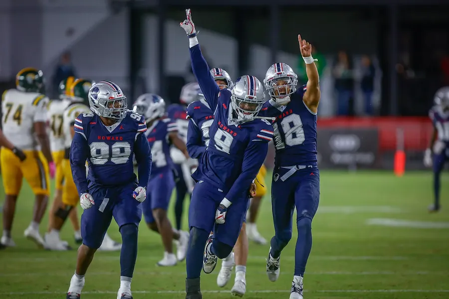 Football players in blue uniforms celebrate on a lit field at night