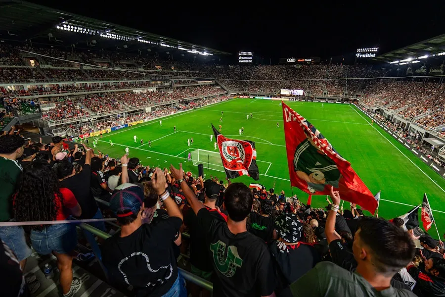 Fans wave large red flag in packed soccer stadium at night