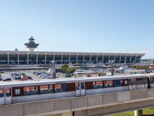 Aeropuerto Internacional de Dulles con dos vagones de Metro corriendo frente a él.