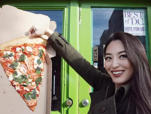 Woman holding up a giant piece of pizza next to her face