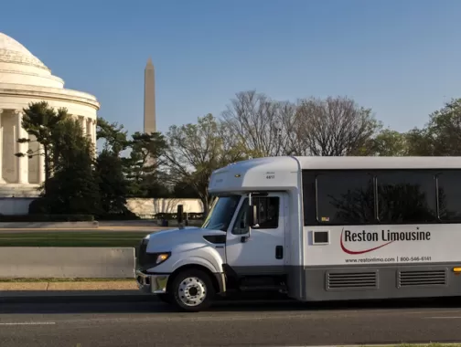 Reston Limousine bus in front of the Jefferson Memorial with the Washington Monument in the background.