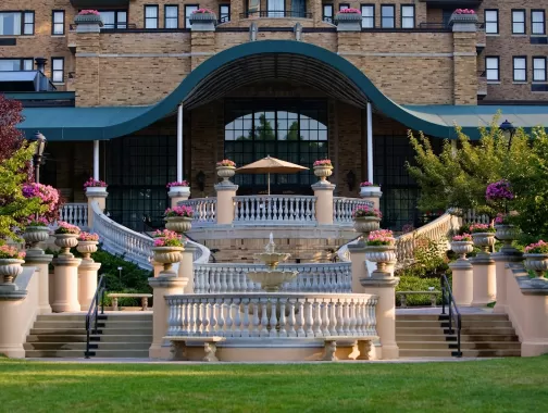Una gran escalera y una terraza adornada con jardineras repletas de flores conducen a la elegante entrada del histórico Omni Shoreham Hotel en Washington, DC.