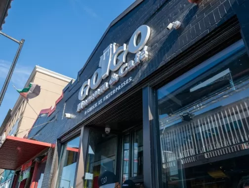 The entrance to the Go-Go Museum & Café features bold signage on a black-painted brick building under a bright blue sky.