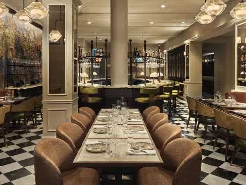 Elegant restaurant interior at Sixty DC featuring warm lighting, modern decor and a central bar with high stools.
