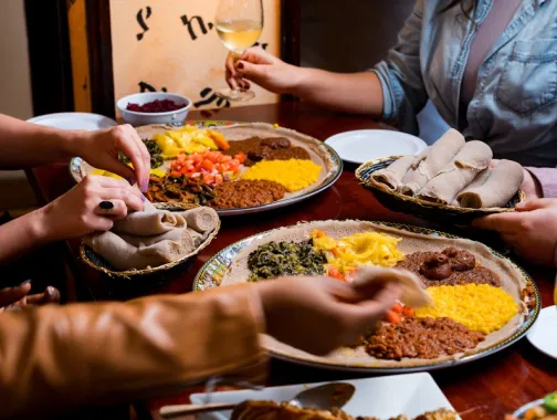 A colorful spread of Ethiopian dishes featuring injera, stews and fresh vegetables.