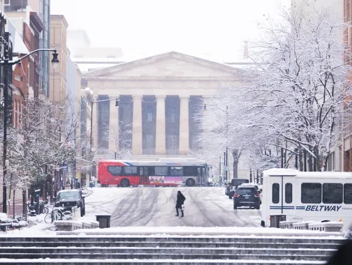 A snowy scene of a downtown street leading up to the National Archives in Washington, DC. 
