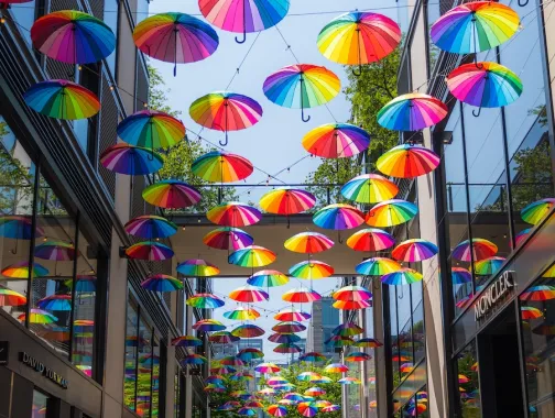 Colorful umbrellas hanging in a covered walkway between tall buildings