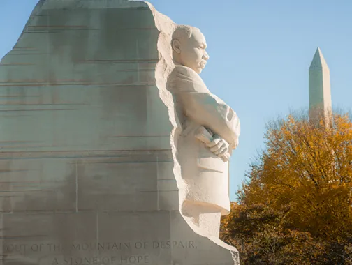Martin Luther King Jr. Memorial statue with Washington Monument behind, autumn trees