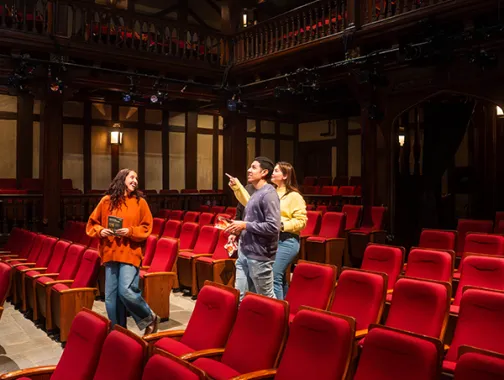 Three people chatting among red seats inside Ford’s Theatre