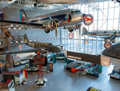 Aircraft hangar with jets suspended overhead and visitors below