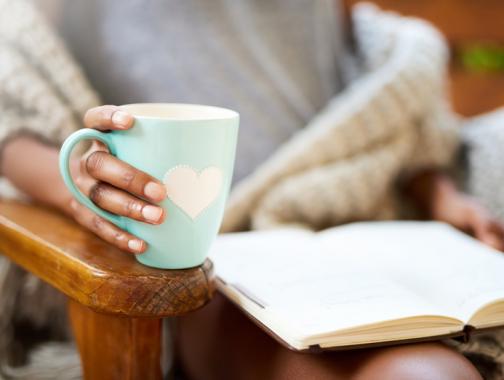 Woman holding mug and reading a book