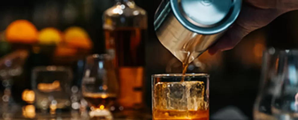 Bar tender pouring whiskey into a glass