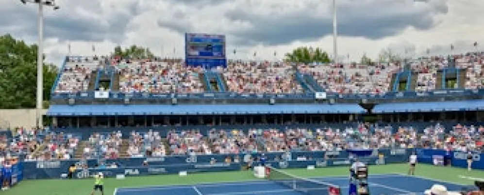 Tennis match in progress at the Citi Open with a crowd of spectators in the stands at the venue in Washington, DC.