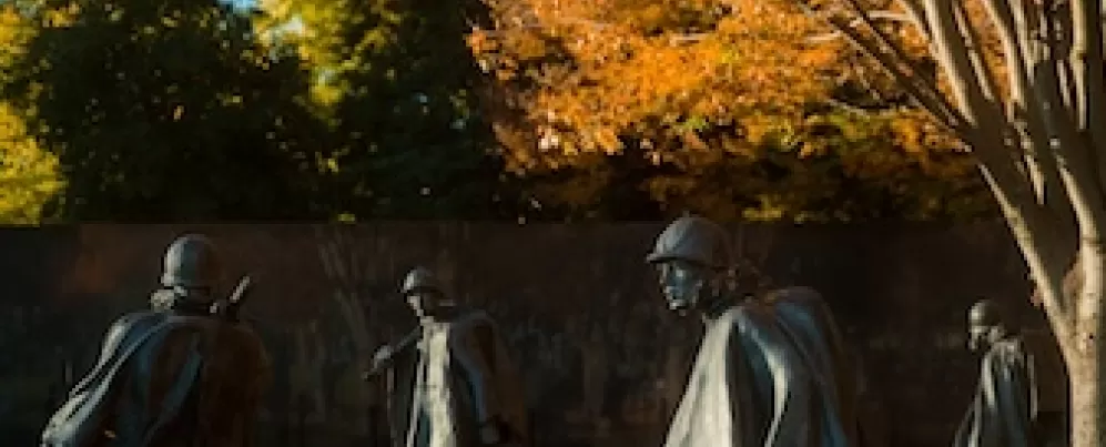 Varias figuras del Memorial de los Veteranos de la Guerra de Corea con árboles otoñales.