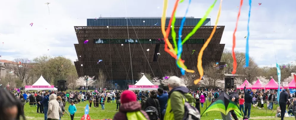 Uma cena colorida do Blossom Kite Festival com pipas voando no céu em frente ao Museu Nacional de História e Cultura Afro-Americana.