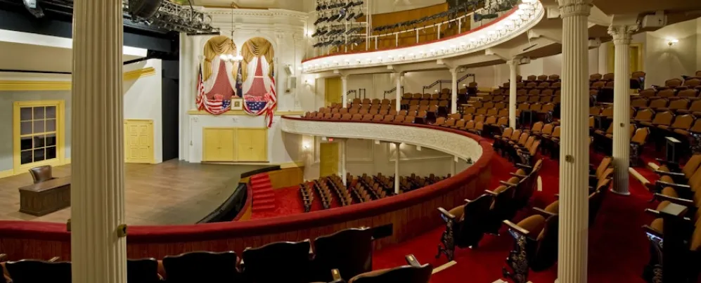 The historic Ford's Theatre features elegant red seating, curved balconies, and a stage framed by rich gold accents.