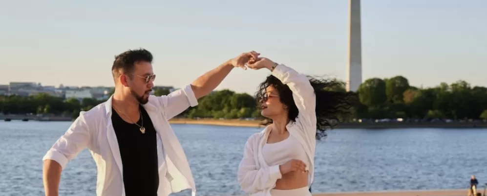 Zwei Menschen tanzen mit dem Washington Monument im Hintergrund. 