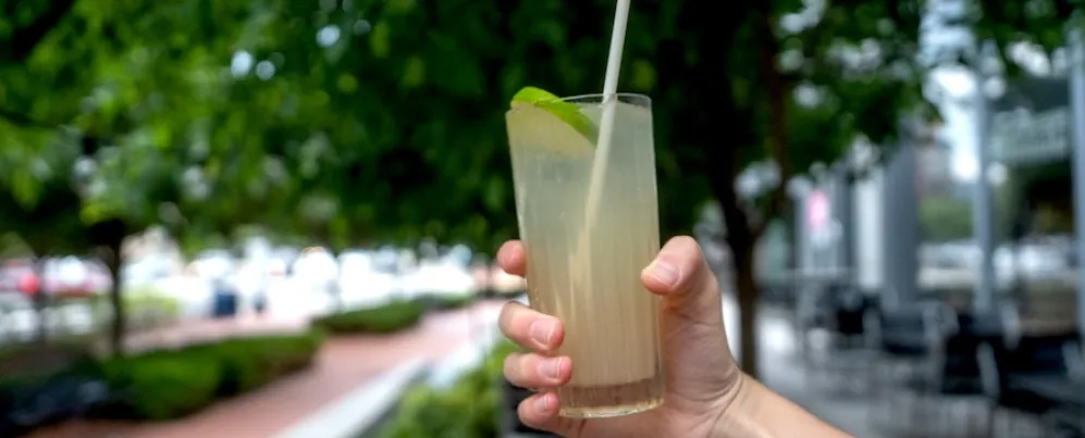  A hand holds out a refreshing green cocktail with lime. 