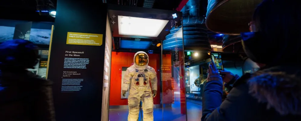 Um visitante tira uma foto do traje espacial Apollo 11 de Neil Armstrong, exposto atrás de um vidro.