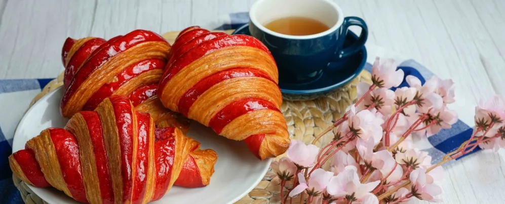 桌上擺放著乳蛋餅、三明治、覆盆子羊角麵包、甜點、櫻桃和咖啡。