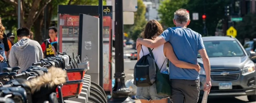 Una pareja camina del brazo junto a una fila de bicicletas de Capital Bikeshare en el vecindario Adams Morgan de Washington, DC.