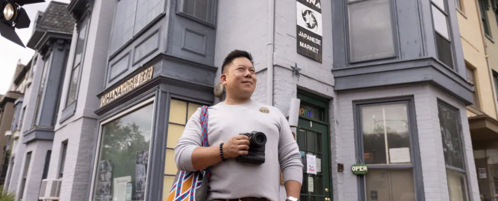 一位拿著相機的遊客站在華盛頓特區 Ohana 日本市場外。