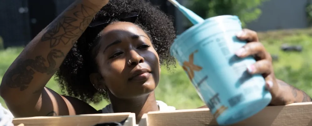 Um artista mergulha um pincel em um recipiente com tinta de cores brilhantes. 