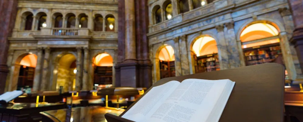 An open book rests on a lectern inside the ornate reading room of the Library of Congress.