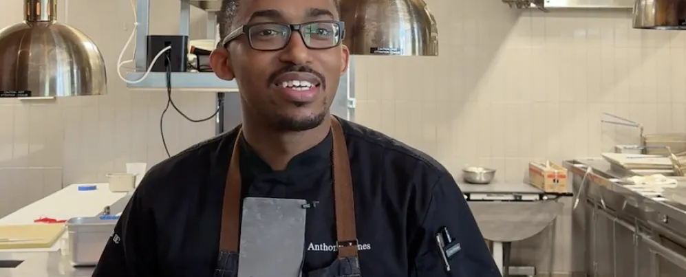 Chef in an apron holding a microphone in a restaurant kitchen