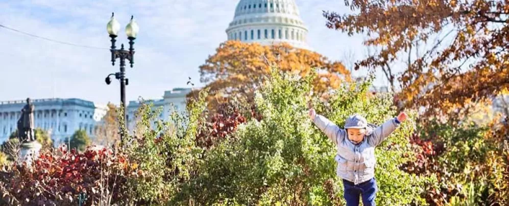 @chasingkaiphoto - Criança pulando em frente ao prédio do Capitólio dos EUA cercada por folhagem de outono - Outono em Washington, DC