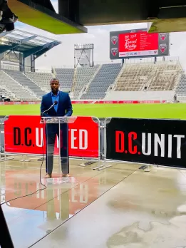 Elliott Ferguson falando com Audi Field ao fundo