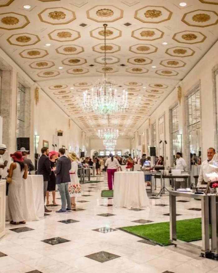 Guests mingle and enjoy food and drinks in an elegant marble hall at The Mayflower Hotel in Washington, DC.