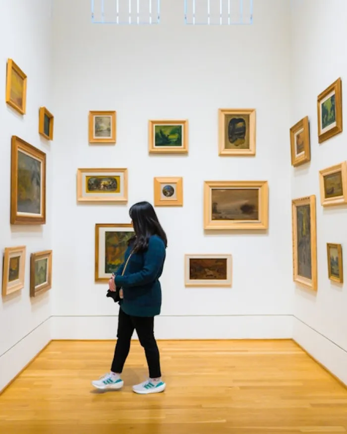 Visitor views framed paintings in white Phillips Collection gallery with wood floor