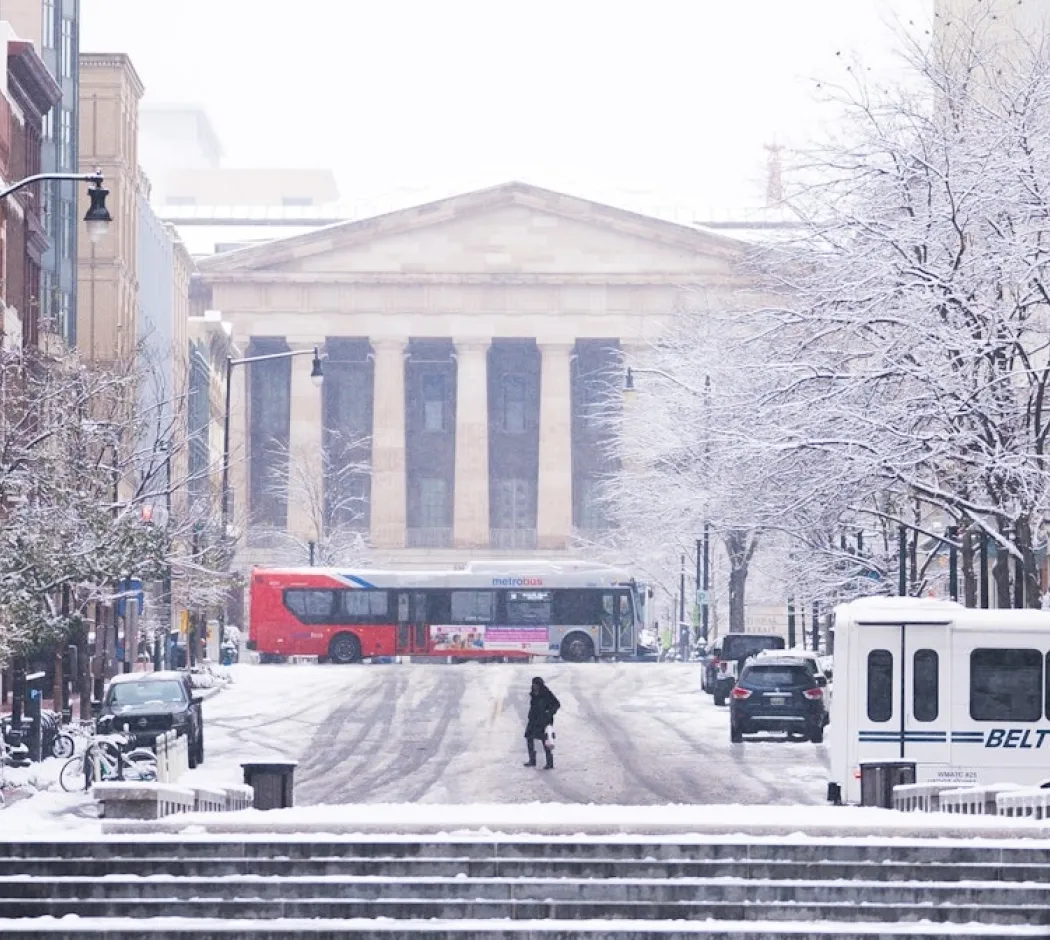 A snowy scene of a downtown street leading up to the National Archives in Washington, DC. 
